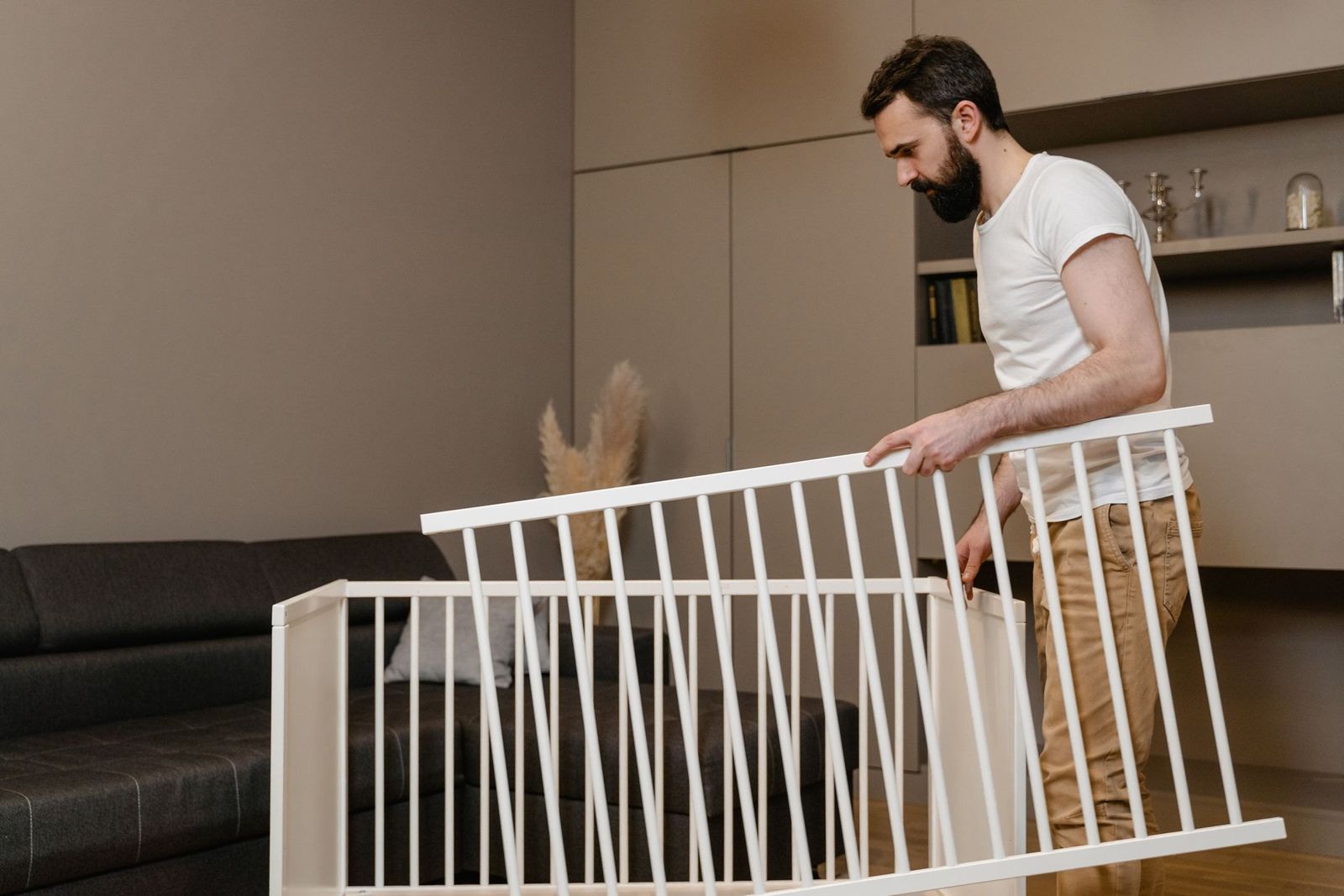 Monteur baut im Wohnzimmer ein Kinderbett auf
